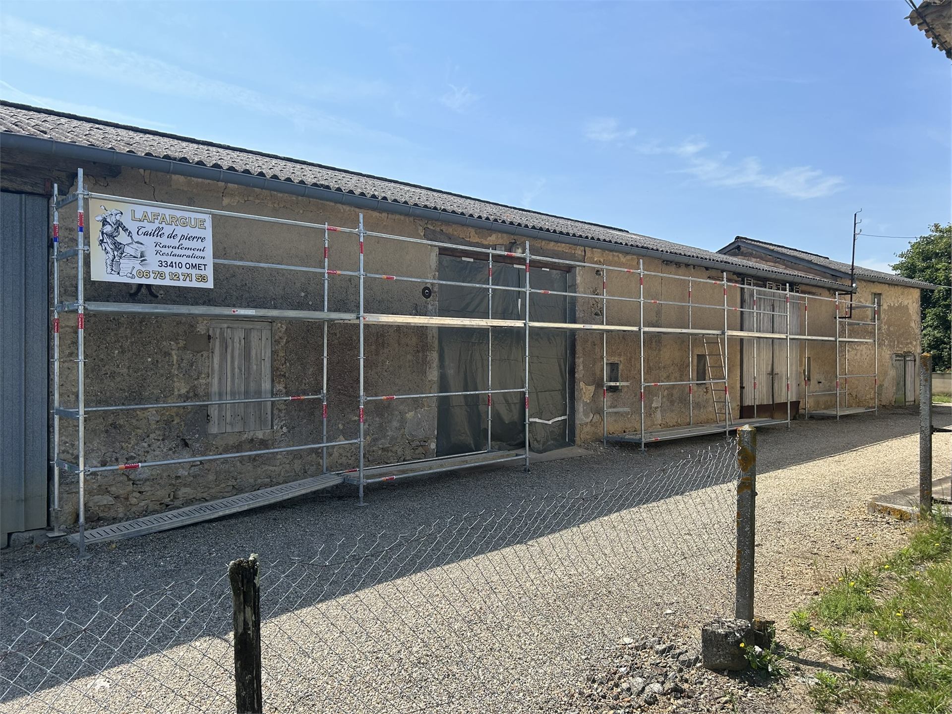 Grange en pierre en chantier avec échafaudage avant restauration