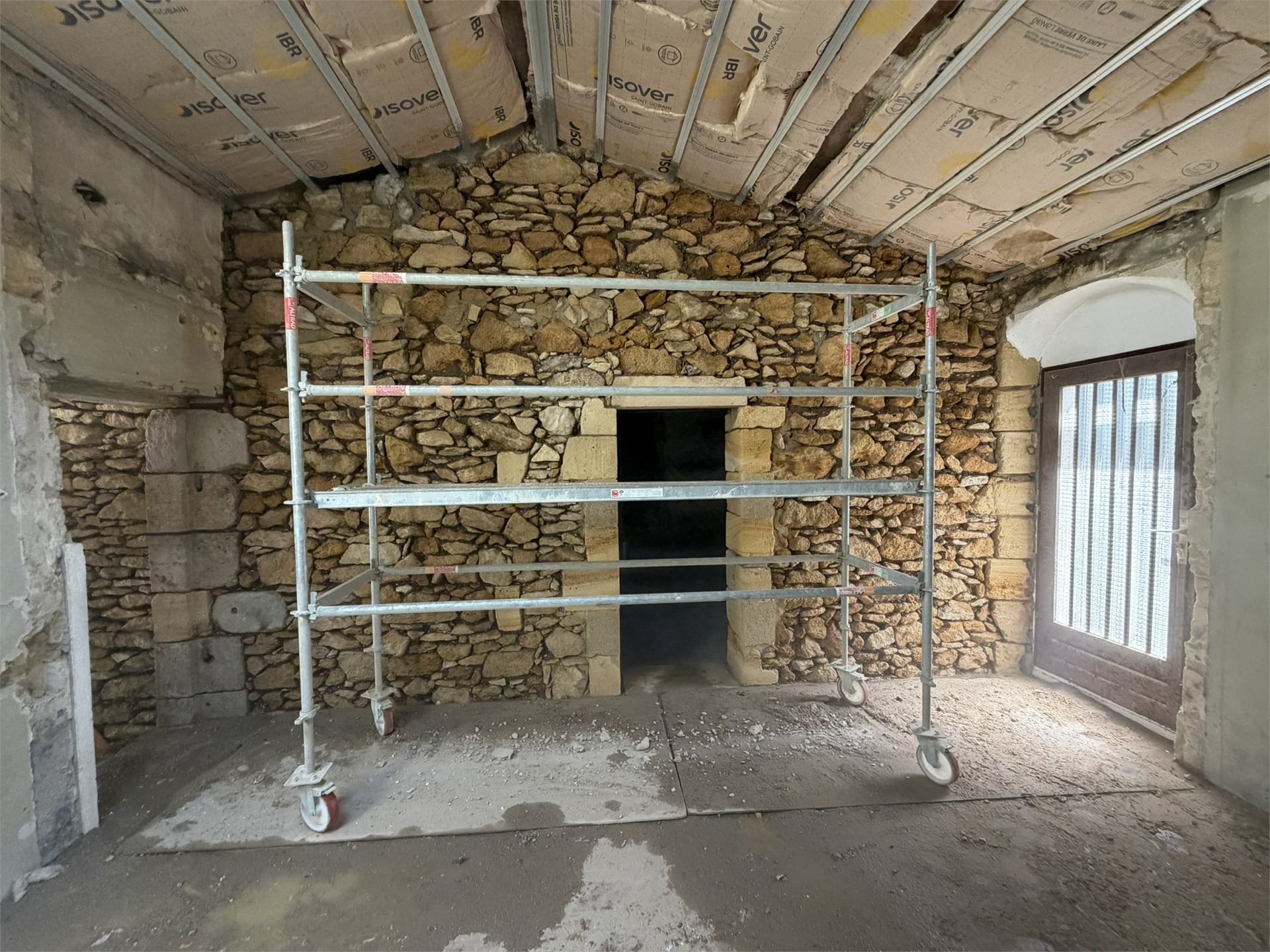 Mur en pierre brute avec échafaudage avant piquage, chantier medhi