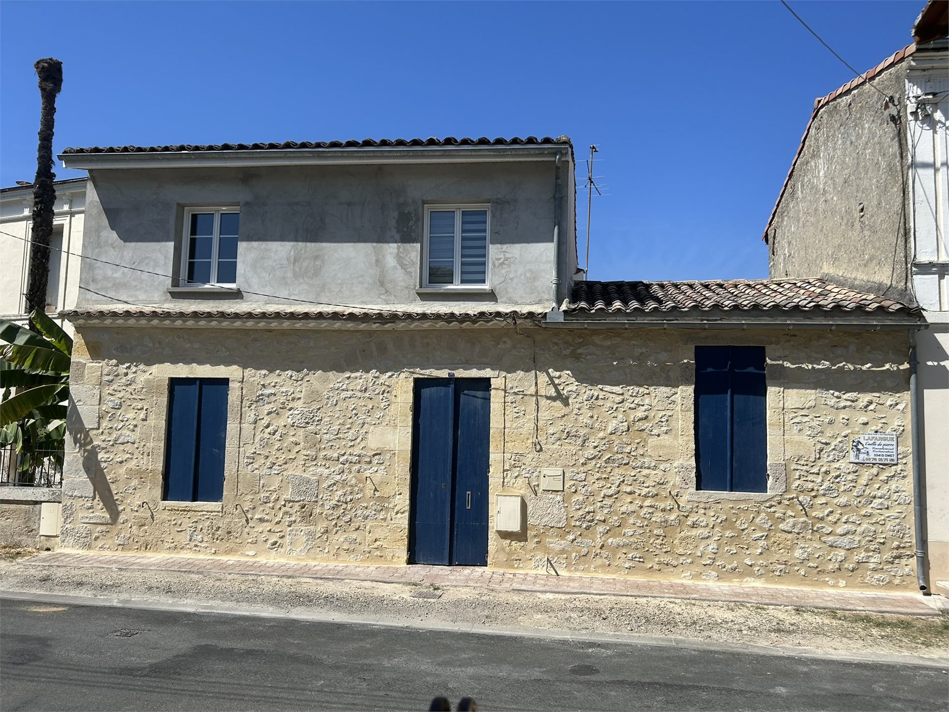 Façade de maison restaurée avec enduit propre et volets bleus