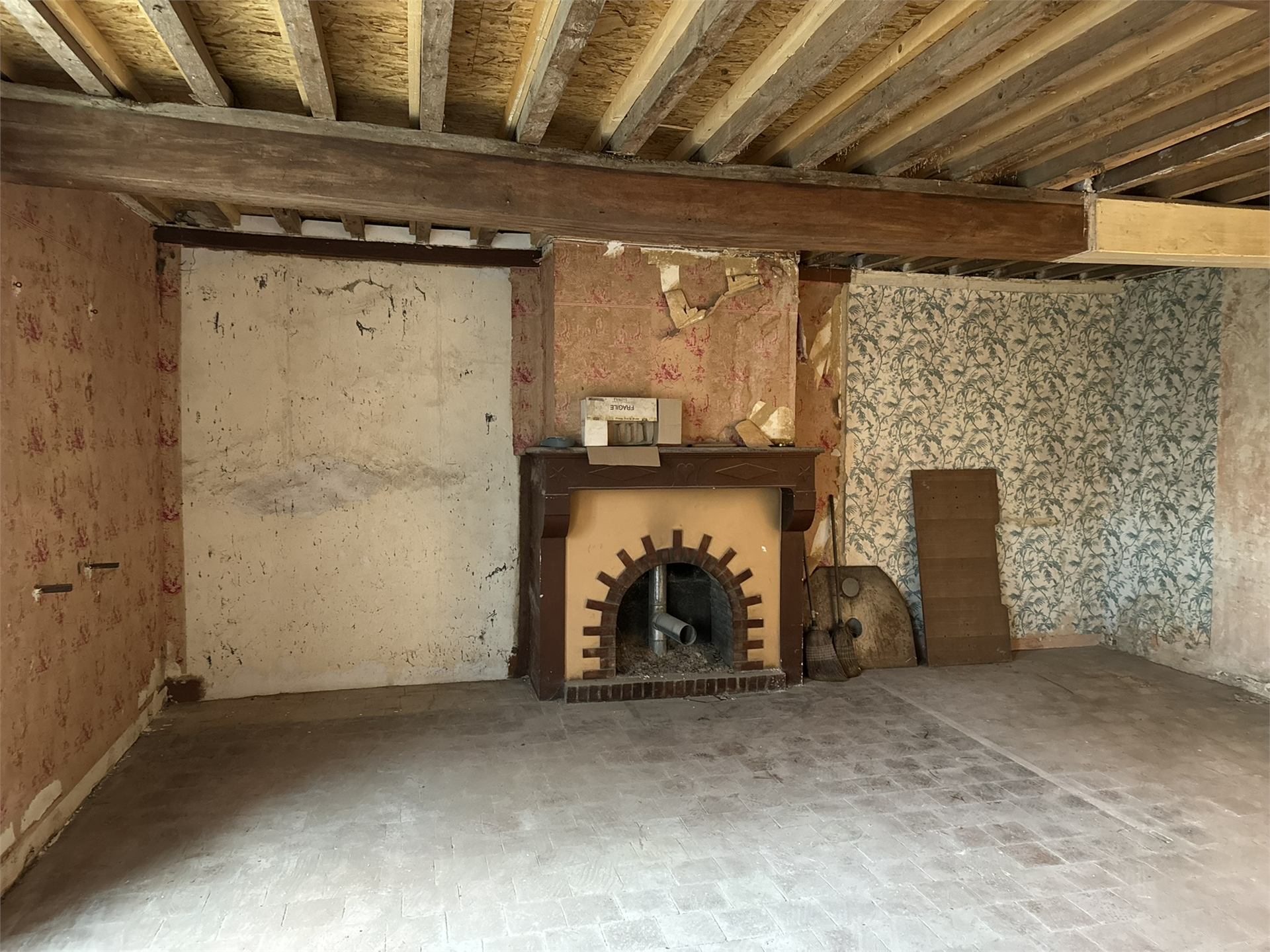 Pièce avec ancienne cheminée et papier peint dégradé avant restauration