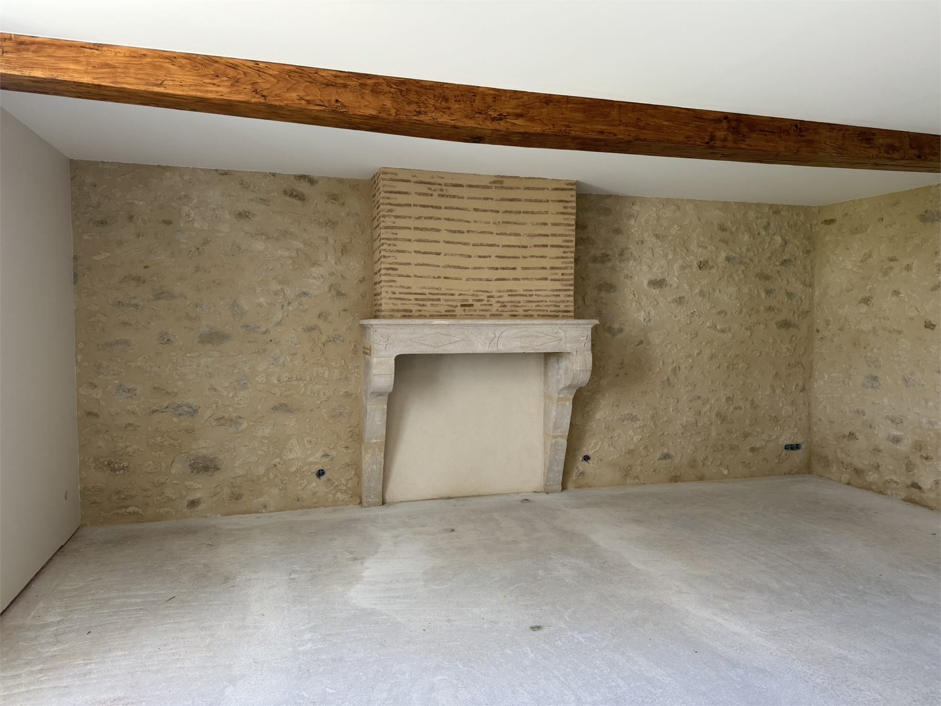Cheminée en pierre restaurée avec manteau sculpté et mur en pierre apparente