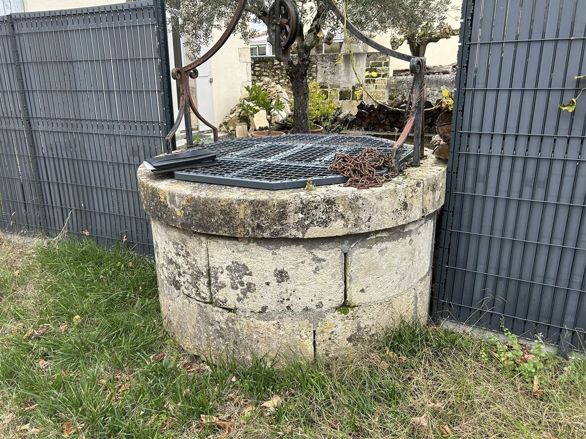 Puits ancien en pierre fissurée et tachée avant restauration